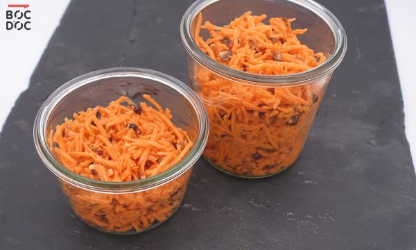 Bocaux de carottes râpées soupoudrées d'amandes sur une ardoise